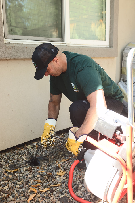 Beaver Brothers technician feeding a drain cleaning cable into an outdoor cleanout